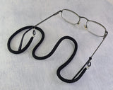 Eyeglasses with a black braided cord on a light gray background