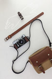 Three leather watch straps in dark brown, medium brown, and black, each with silver-toned metal buckles, laid out vertically on a light textured background.