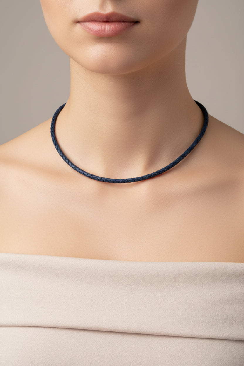 Blue braided leather necklace with a silver clasp on a stone surface