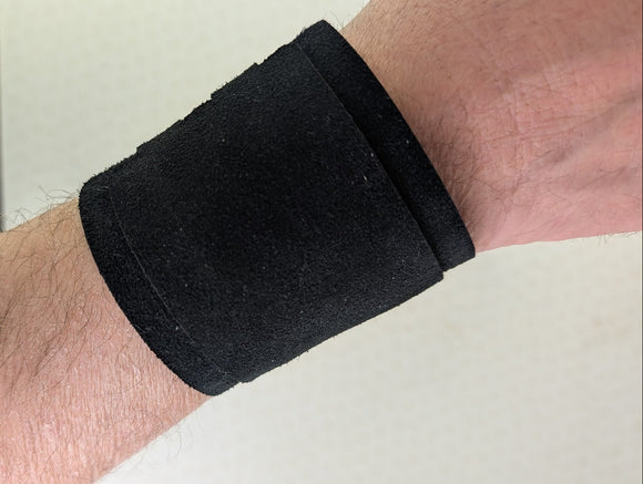 Black wrist support brace on a person's wrist against a neutral background